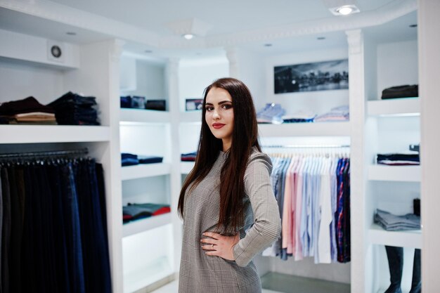 Hermosa chica morena en la boutique de la tienda de ropa en vestido gris