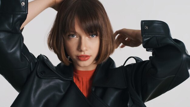 Hermosa chica morena con cabello bob y labios rojos mirando con confianza a la cámara sobre fondo blanco