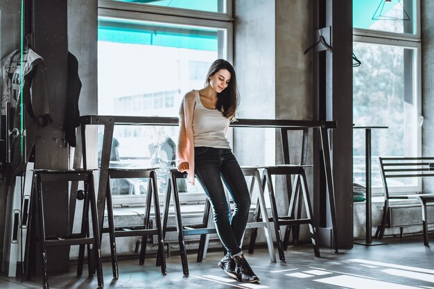 hermosa chica morena en café con interior en estilo loft