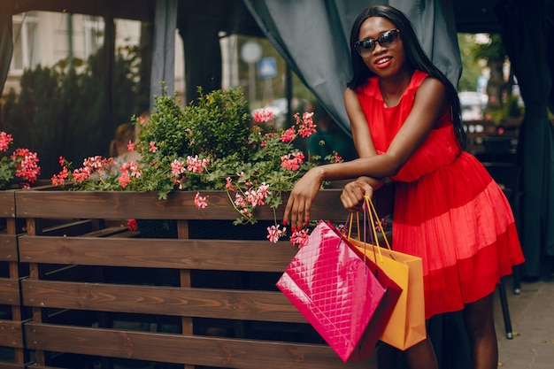 Hermosa chica negra con bolsas de compras en una ciudad