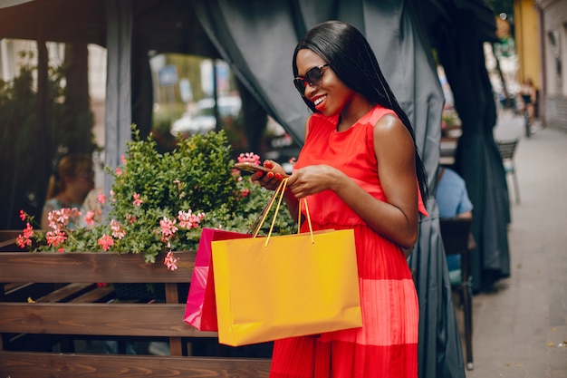 Hermosa chica negra con bolsas de compras en una ciudad