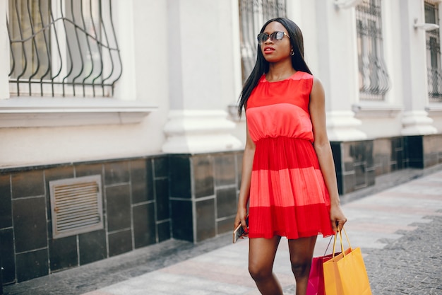 Hermosa chica negra con bolsas de compras en una ciudad