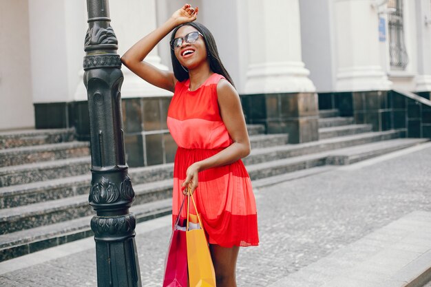 Hermosa chica negra con bolsas de compras en una ciudad