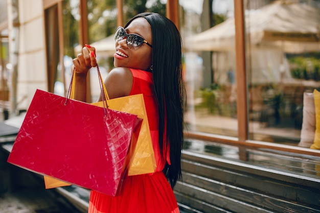 Hermosa chica negra con bolsas de compras en una ciudad