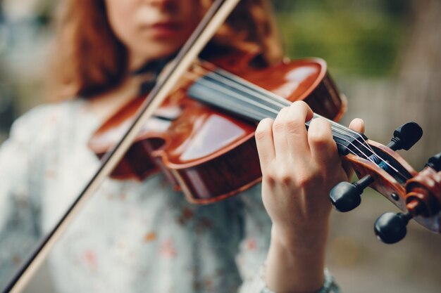 Hermosa chica en un parque de verano con un violín