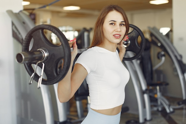 Una hermosa chica participa en un gimnasio con una barra