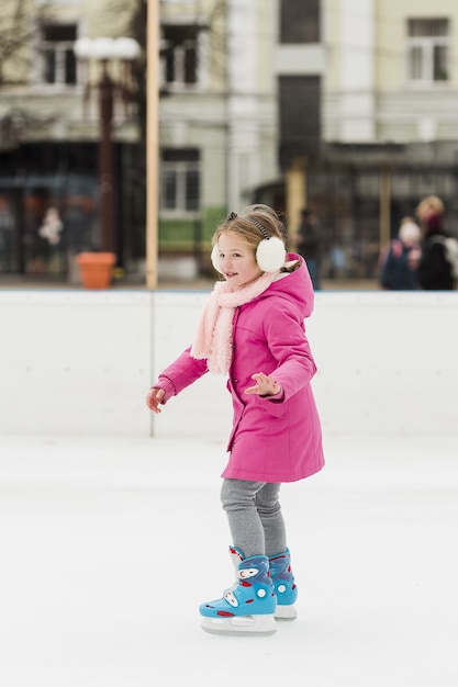 Foto gratuita hermosa chica patinar sobre hielo tiro completo