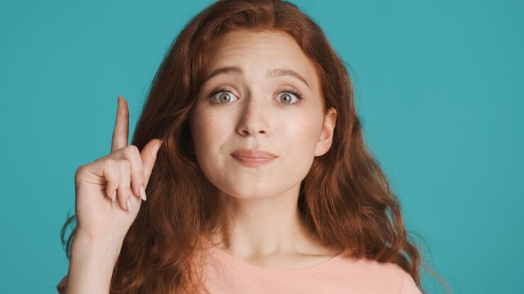 Foto gratuito hermosa chica pelirroja emocionada levantando el dedo con una nueva idea sobre un fondo colorido