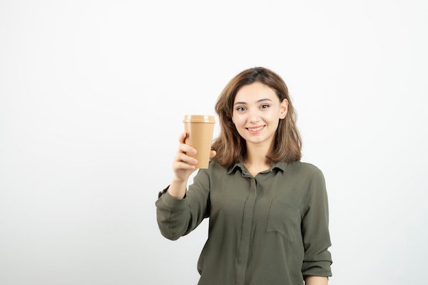 Hermosa chica de pelo corto con taza de café de pie y mirando.