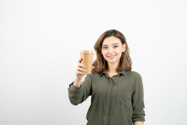 Hermosa chica de pelo corto con taza de café de pie y mirando.