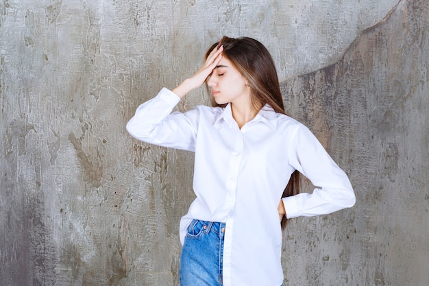 Foto gratuita hermosa chica de pelo largo en blusa blanca con dolor de cabeza