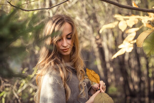 hermosa chica con el pelo largo en el bosque de otoño, concepto de temporada de otoño
