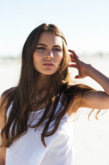 Hermosa chica con el pelo largo morena y la parte superior blanca