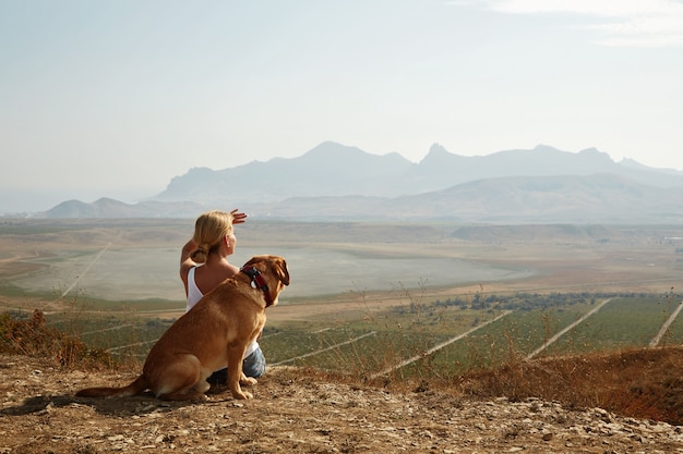 Foto gratuita hermosa chica con un perro en la cima de la montaña