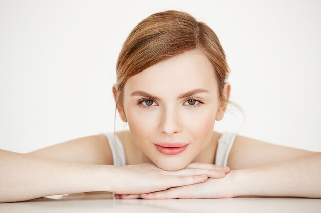 Hermosa chica con piel limpia perfecta sonriendo sentado en la mesa. Spa de belleza y cosmetología.