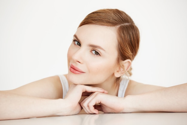 Hermosa chica con piel limpia perfecta sonriendo sentado en la mesa. Spa de belleza y cosmetología.