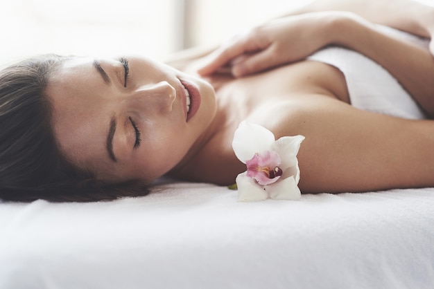 Hermosa chica con una piel perfecta de orquídea cerca de la ventana grande.