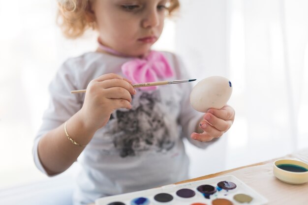 Hermosa chica pintando en huevo