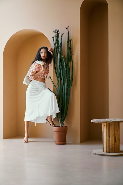 Foto gratuita hermosa chica posando en arco decorativo con maceta de cactus