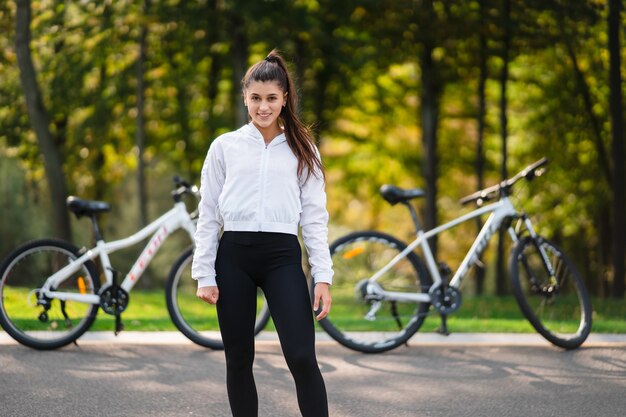 Hermosa chica posando en bicicleta blanca. Camina en la naturaleza.