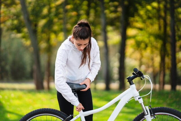 Hermosa chica posando en bicicleta blanca. Camina en la naturaleza.