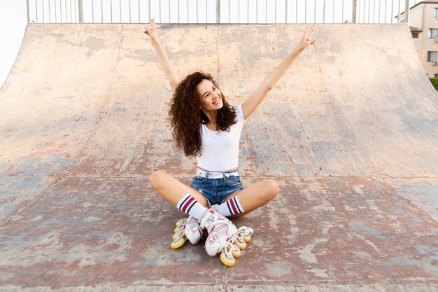 Hermosa chica posando en patines mientras está sentado