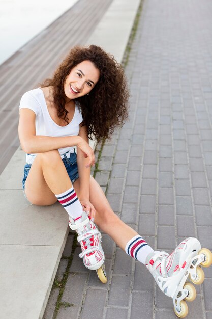 Hermosa chica posando sentada y usando sus patines