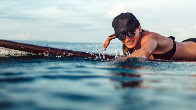 Hermosa chica posando sentado en una tabla de surf en el océano