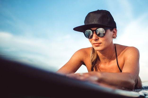 Foto gratuita hermosa chica posando sentado en una tabla de surf en el océano