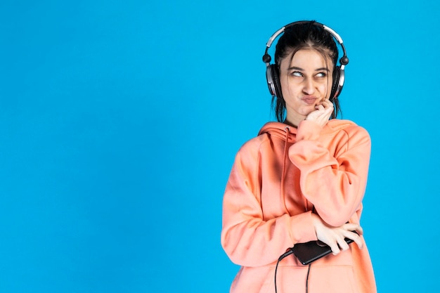 Una hermosa chica puso sus manos lastimándote ahora mirando a un lado mientras escucha música en sus auriculares Foto de alta calidad