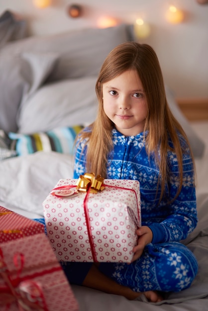 Hermosa chica con regalo de Navidad en la cama