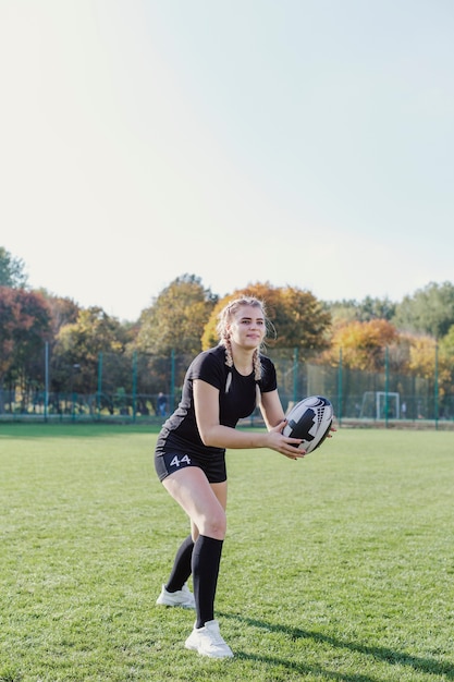 Hermosa chica rubia atrapando una pelota de rugby