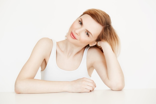 Hermosa chica rubia natural sonriendo sentado en la mesa. Concepto de belleza y salud.