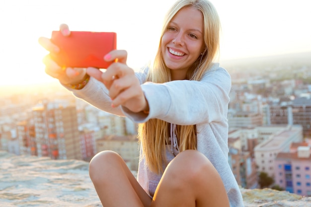 Hermosa chica rubia tomar un selfie en el techo.