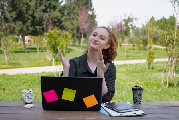 Hermosa chica sentada trabajando en una laptop mostrando mirando hacia arriba sonriendo