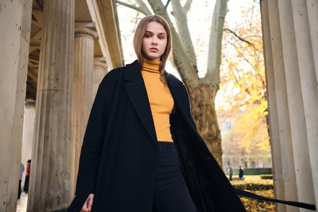 Hermosa chica seria y elegante posando con confianza en la cámara en una hermosa calle de la ciudad