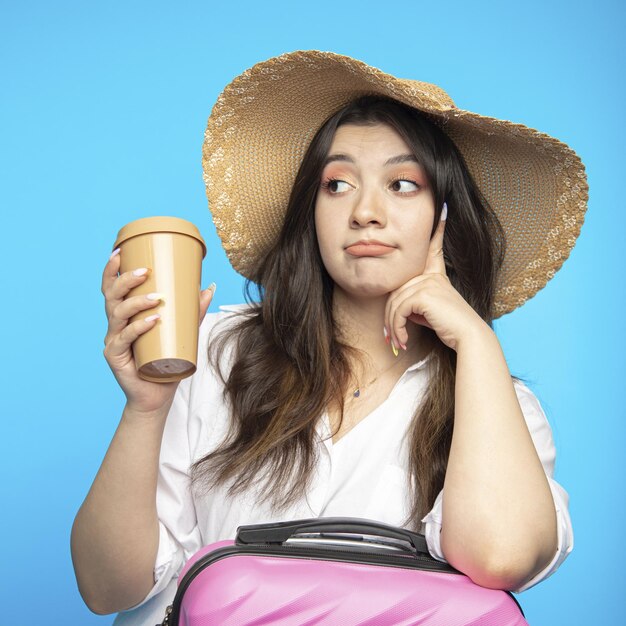 Hermosa chica sonriente con sombrero se va de vacaciones y quiere descansar