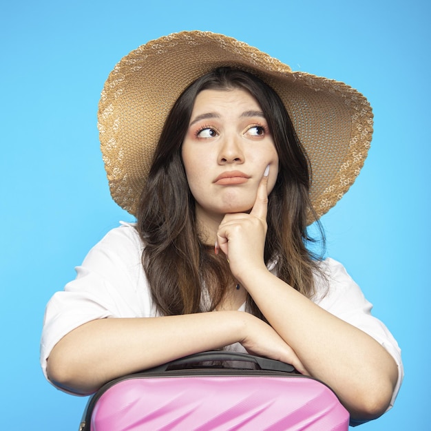 Hermosa chica sonriente con sombrero se va de vacaciones y quiere descansar