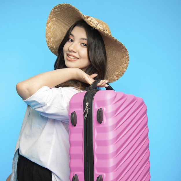 Hermosa chica sonriente con sombrero se va de vacaciones y quiere descansar