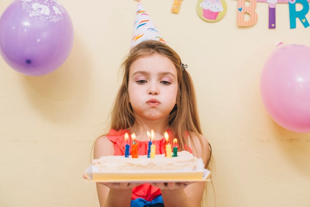 Hermosa chica soplando velas en la torta