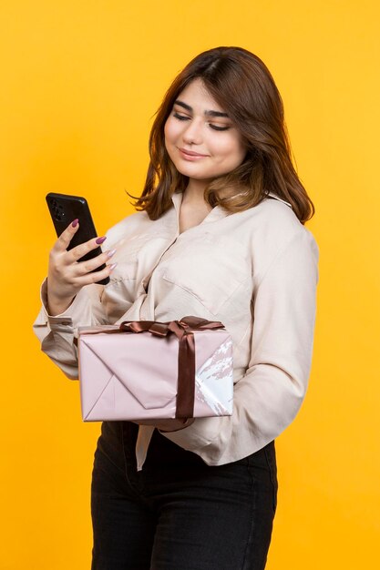 Hermosa chica sosteniendo una caja de prisión y mirando su teléfono Foto de alta calidad