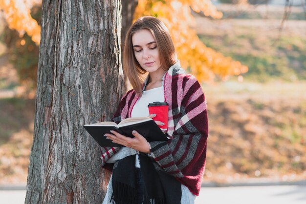 Hermosa chica sosteniendo un libro y una taza