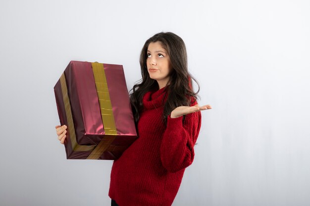 Hermosa chica sosteniendo un regalo de Navidad y mirando hacia arriba.