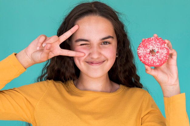 Hermosa chica sosteniendo una rosquilla glaseada