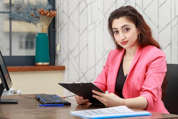 Hermosa chica sosteniendo su cuaderno y sonriendo a la cámara Foto de alta calidad