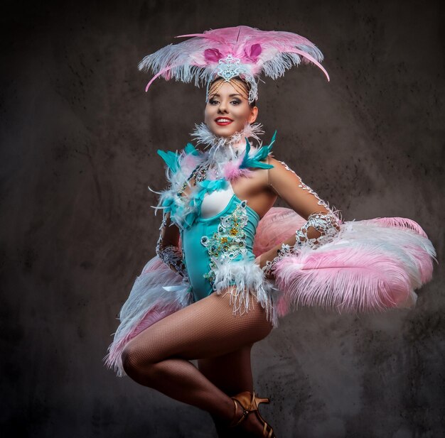 Hermosa chica en un suntuoso traje de plumas de carnaval. Aislado en un fondo oscuro.