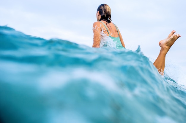 Hermosa chica surfista está nadando a bordo