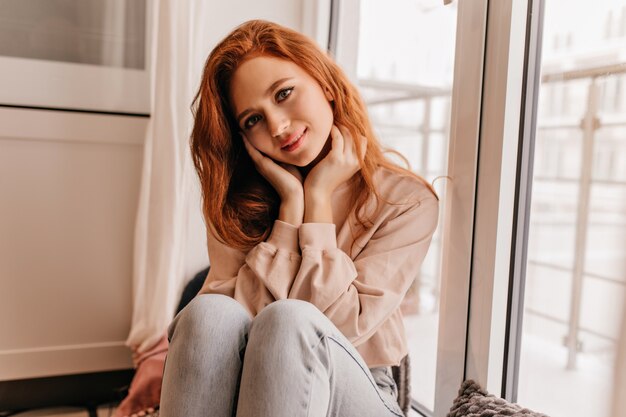 Hermosa chica tímida con cabello oscuro posando en casa. Señora sensual de jengibre pasar tiempo en su habitación.