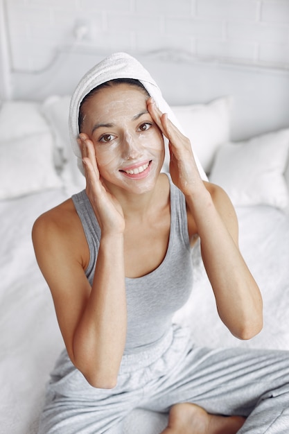 Hermosa chica con una toalla usando un producto de belleza
