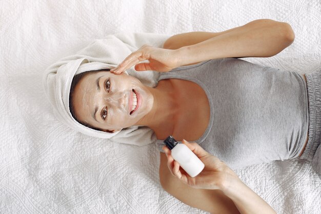 Hermosa chica con una toalla usando un producto de belleza